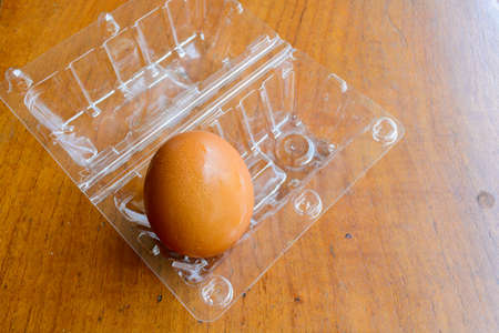 Brown eggs in the plastic box on wooden background