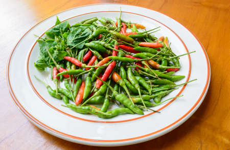 Green, red chili peppers on white dishの写真素材