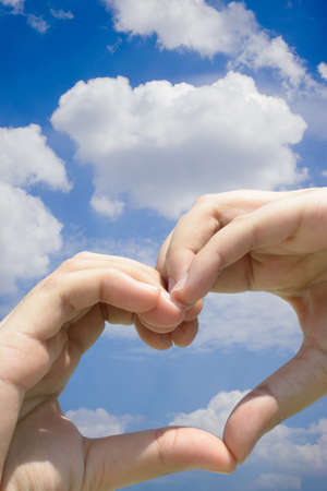 Girl hand in heart form love blue skyの写真素材