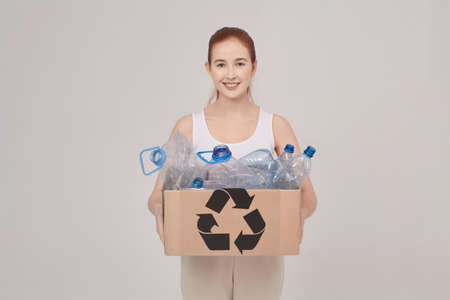 girl hold a box for recycling, she hold in hands box with plastic, eco concept, girl on the white backgroundの写真素材