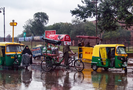 New Dehli, India - March 01, 2015: cycle rickshaw and a passenger try to make headway, despite the heavy rain and the increasingly risky rising water level.のeditorial素材