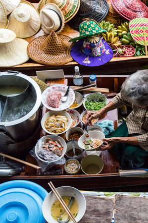Food vendor at the Damnoen Saduak Floating Market preparing Thai style food Thailand.の写真素材