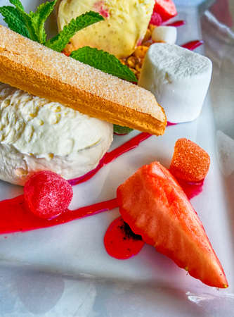 Bright ice cream dessert with candy and strawberry close upの写真素材