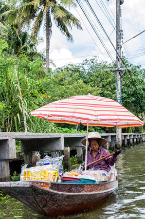 A lady selling fruit from her boat at a floating market in Thailand. Image taken at Damnoen Saduak floating market near Bangkok.のeditorial素材