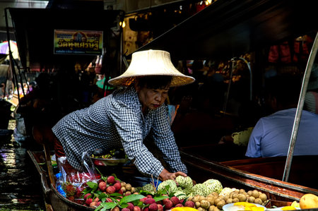 A lady selling fruit from her boat at a floating market in Thailand. Image taken at Damnoen Saduak floating market near Bangkok.のeditorial素材