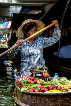 A lady selling fruit from her boat at a floating market in Thailand. Image taken at Damnoen Saduak floating market near Bangkok.のeditorial素材