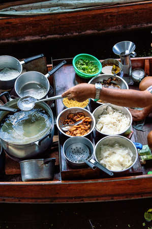 Food vendor at the Damnoen Saduak Floating Market preparing Thai style food Thailand.の写真素材