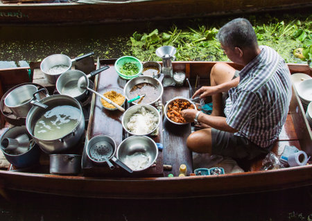 Food vendor at the Damnoen Saduak Floating Market preparing Thai style food Thailand.のeditorial素材