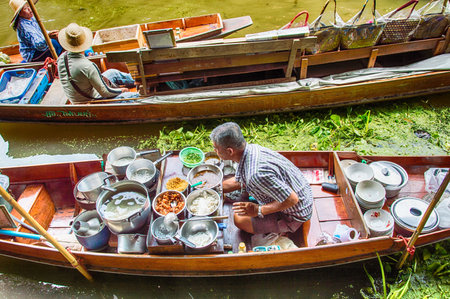 Food vendor at the Damnoen Saduak Floating Market preparing Thai style food Thailand.のeditorial素材