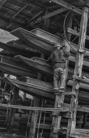 Old man inspecting longboats in thailandのeditorial素材