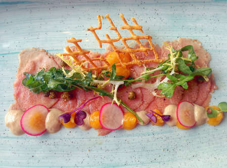 Luxurious Vitello Tonato with peach condiment and some greensの写真素材