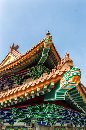 Gilded red wooden roofs in traditional Chinese-style at the Buddhist temple and postern of the Po...