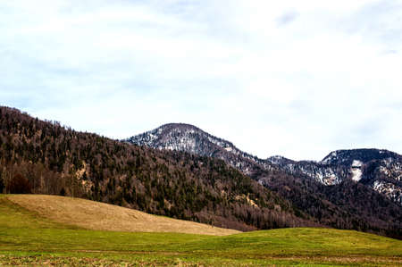 Landscape shot of rolling hils in austria with mountains in the backgorundの写真素材