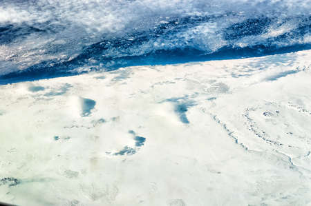 Aerial Shot of the Barents Sea with chunks of ice breaking of the main land