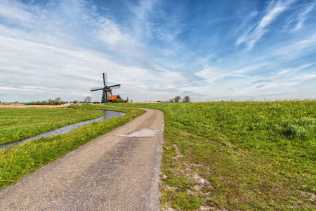 Rural road and windmill in Netherlandsの写真素材
