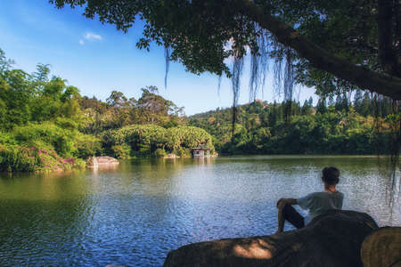 A man looking over the beautiful Wanshi lake at Xiamen's Botanical Gardensの写真素材