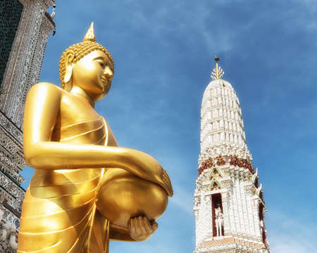 The sculpture of Golden Buddha is standing with both hands holding an alms bowl.の写真素材