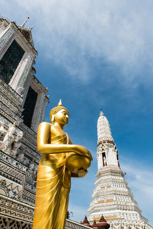 The sculpture of Golden Buddha is standing with both hands holding an alms bowl.の写真素材