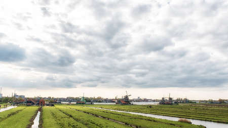 windmills at Zaanse Schans, an industrial and national Dutch heritage site and famous tourist destination in the municipality of Zaandam, the Netherlands. Zaanse Schans is located on the river Zaan, from which its name derives. Industry in the background.の写真素材