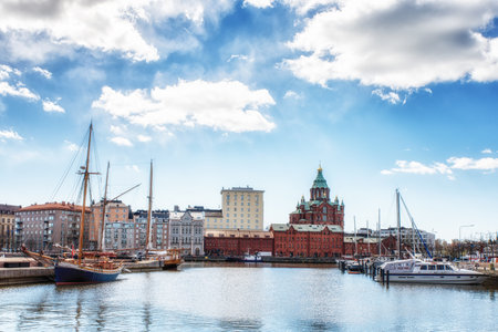 A boat moored in  the north habour in the heart of Helsinki with in the background The iconic domes of Uspenski Cathedral overlooking the redeveloped warehouses.のeditorial素材