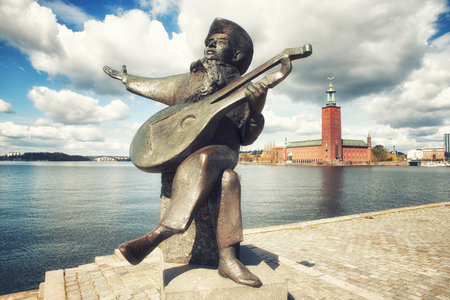 Stockholm, Sweden - May 11, 2017: Statue of Evert Taube, a Swedish author, artist, composer and singer, considered as one Sweden's most respected musicians ever. with Stockholm City hall in background.のeditorial素材