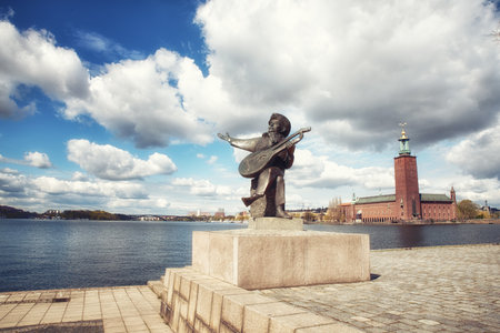 Statue of Evert Taube with Stockholm City Hall on a backgroundのeditorial素材