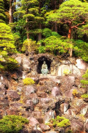 Narita, Japan 17 March, 2018: bonsai trees growing outdoor in a garden on a slope with a statue sitting in a small cave, Naritasan Temple, Narita, Japanのeditorial素材