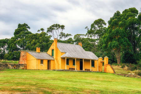 A small house, part of the historic site of Port Arthur, sits on grassy slope.