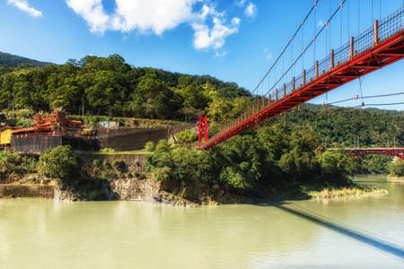 Beautiful red suspension bridge over Nanshi river, Wulai Village, New Taipei City, Taiwanの写真素材