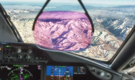 Modern commercial aircraft cockpit with Heads Up Display flying over the Andes near Chili.