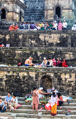 Kathmandu, Nepal - 11 October 2012: People preparing food offerings and praying alongside riverのeditorial素材