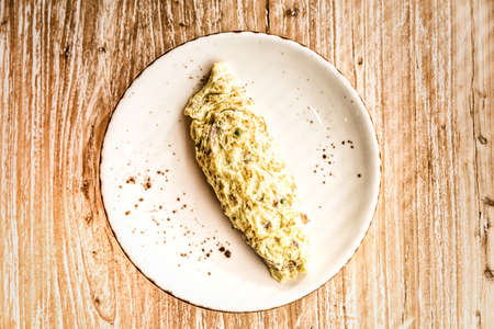 Traditional breakfast omelette on a ceramic plate on wooden background
