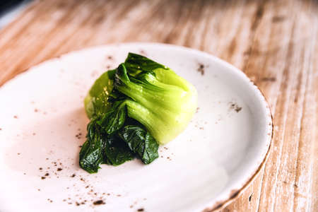 Cooked bok choy  on a ceramic plate on a wooden backgroundの写真素材