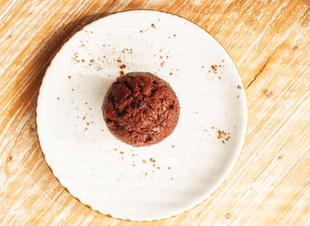 Close up of a delicious chocolate muffin on a brown wooden background with a space for text