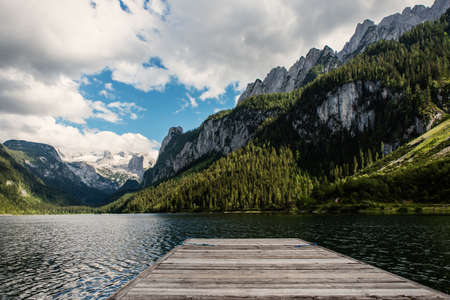 Beautiful Gosausee lake landscape with Dachstein mountains, boat, forest, clouds and reflections in the water in Austrian Alps. Salzkammergut region.の写真素材