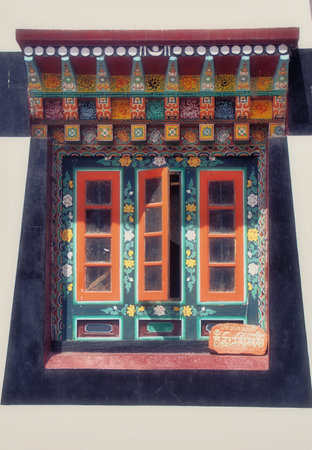 Brightly colored painted carved window and door with purple exterior of Buddhist monastery in the...