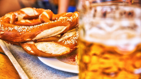 Glass of lager beer with traditional salted pretzels over  wooden background. Top view, Traditional...