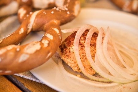 A Bavarian snack: So called Obazda - cheese specialty made of melted camembert with cream cheese and butter, onions, a splash of beer and some spices - served with a pretzelの写真素材