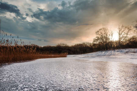 Natural winter forest landscape With frozen lake at sunsetの写真素材