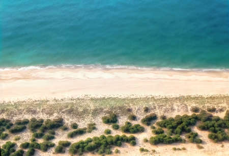 Clean ocean waves breaking on white sand beach with turquoise emerald coloured waterの写真素材