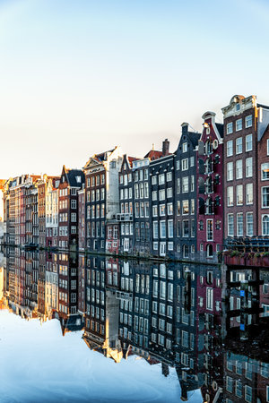 Amsterdam City Scene,  typical dutch houses and their reflection in the canal. Old 17th and 18th century brick houses along a canal in centre of Amsterdam, Netherlands.の素材 [FY310186692283]