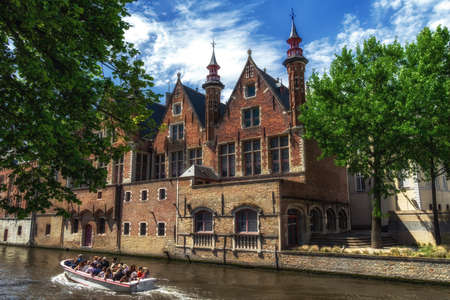 Brugge, Belgium - May 2022: Tourist boat on canal in Bruges in a beautiful summer day, Belgiumの写真素材