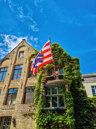 Historic houses with the city flag of Bruges, Belgium.の写真素材