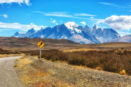 Gravel road in the Torres del Paine National Park. The mountains and rocks are covered with snow and iceの写真素材