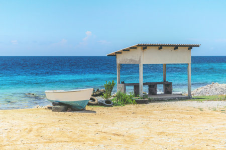 Boat next to a shed on the sandy beach of the caribbean island in bonaire. Netherlands Antilles.の写真素材