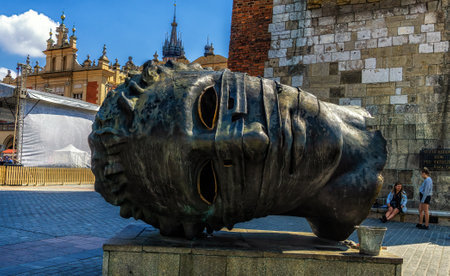 Krakow, Poland - 12 August 2022: Eros Bendato (Eros bound) giant head statue in Rynek Glowny, Krakow. The bronze noggin was sculpted by Igor Mitoraj in 1999 and moved to Krakow in 2003.のeditorial素材