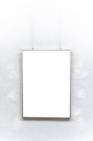 Empty picture frame hanging on white wall.の写真素材