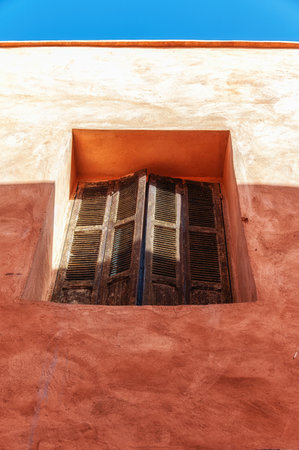 closed window in traditional moroccan house with wall in terracotta red color. Arabic style in architecture.の写真素材