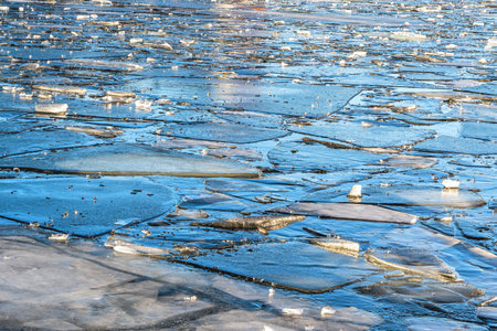 Broken ice near the river bank with hoarfrost and water in winter