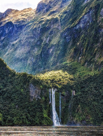 Waterfall cascading down the mountains and fiords of Milford Sound, located in Fiordland National...